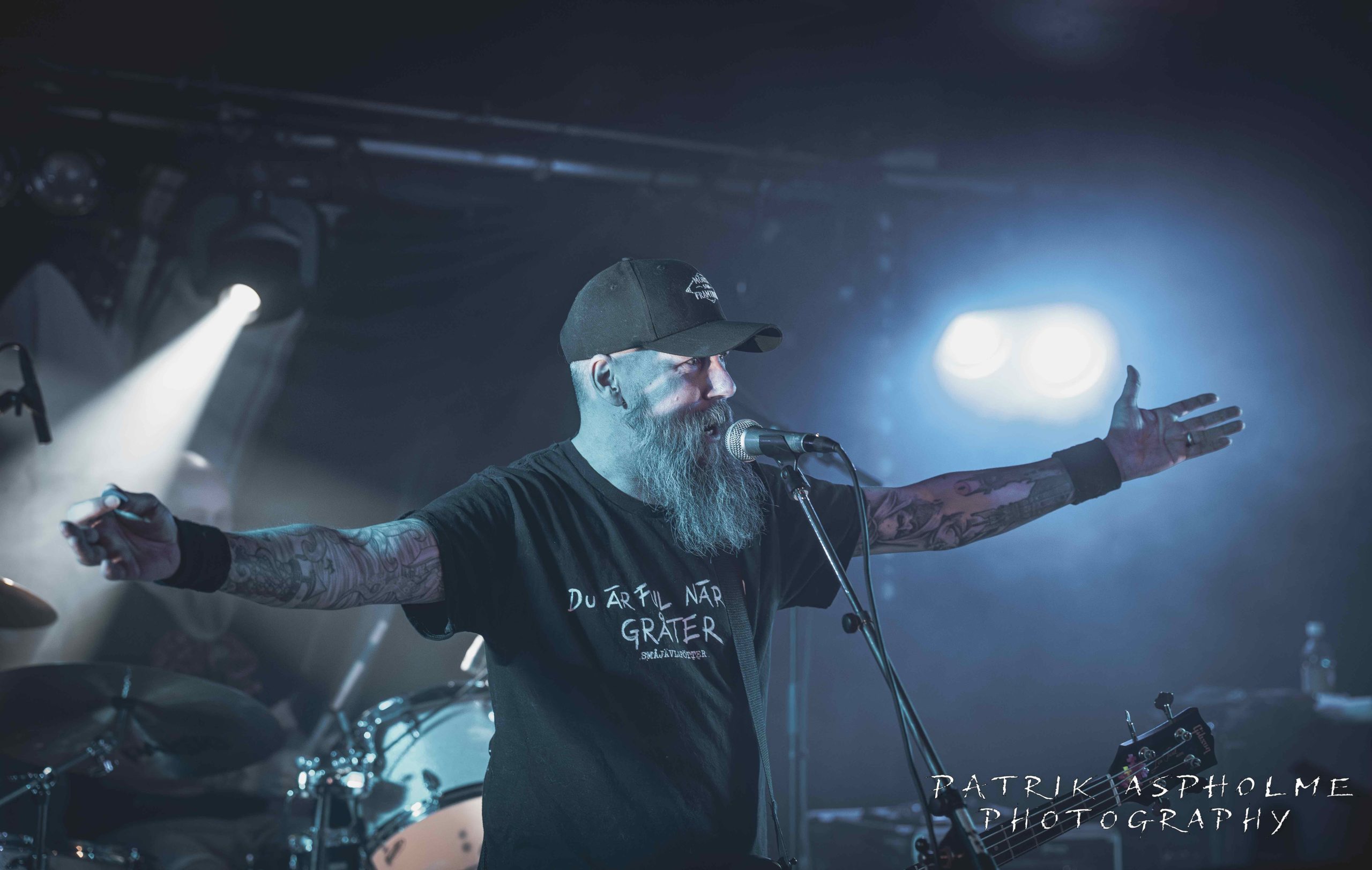 Kardinal Synd står med utsträckta armar och sjunger i mikrofonen.