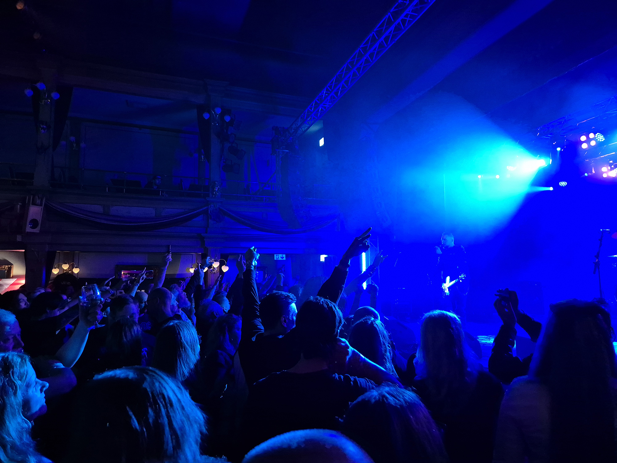 Bandet Edgeland på scenen med ett stort publikhav framför sig i blått scenljus. Några räcker upp händerna mot taket.