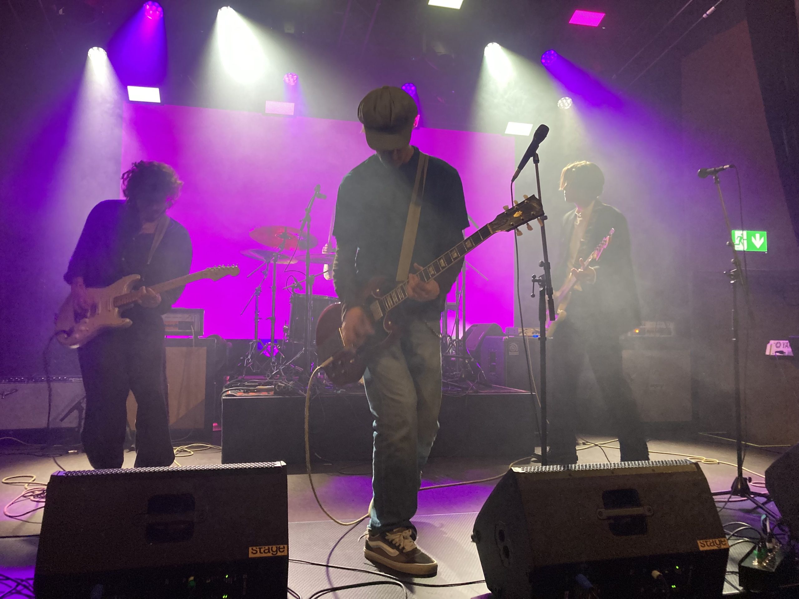 Fyra unga killar på scenen med elgitarr, elbas och en bakom det upphöjda trumsetet.