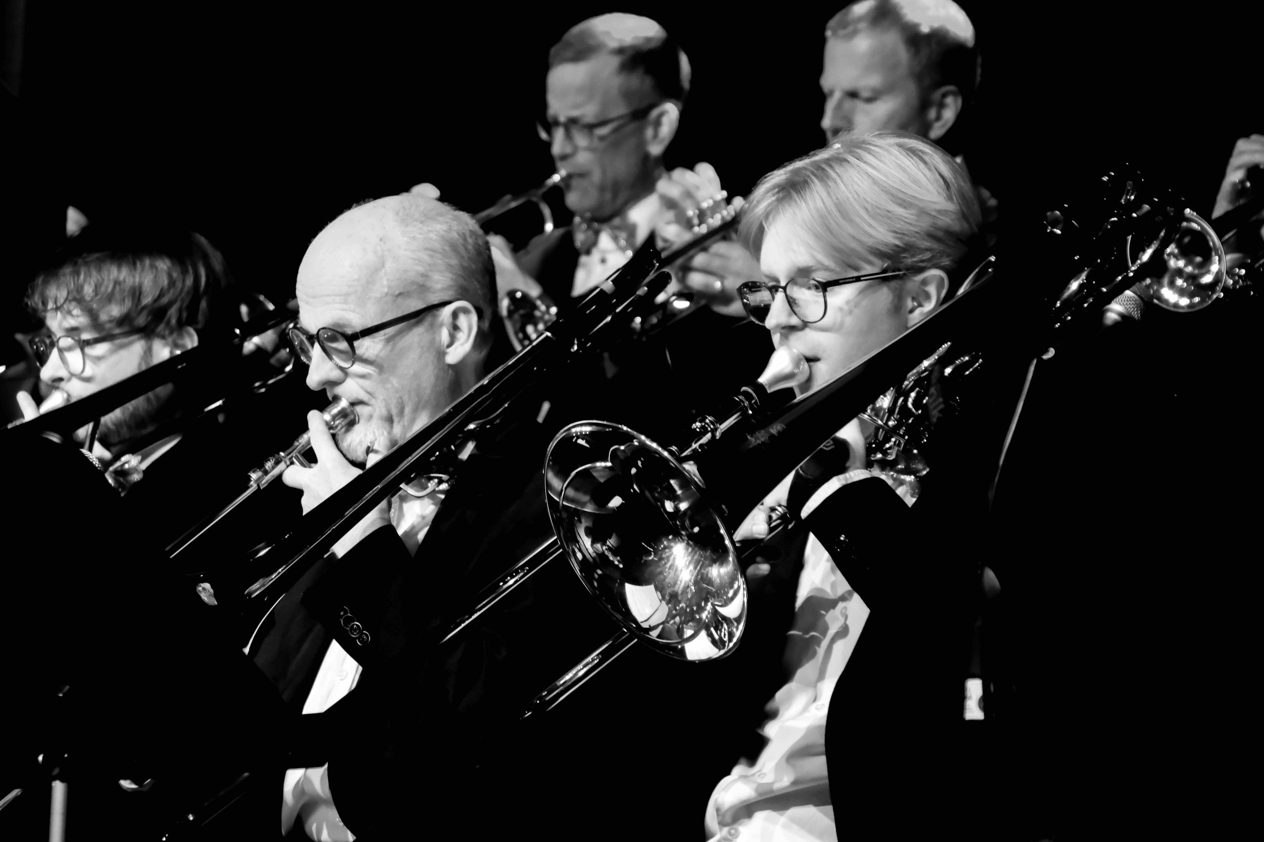 Närbild på trombonsektionen i storbandet. I förgrunden en ung kille och bredvid honom en äldre man.