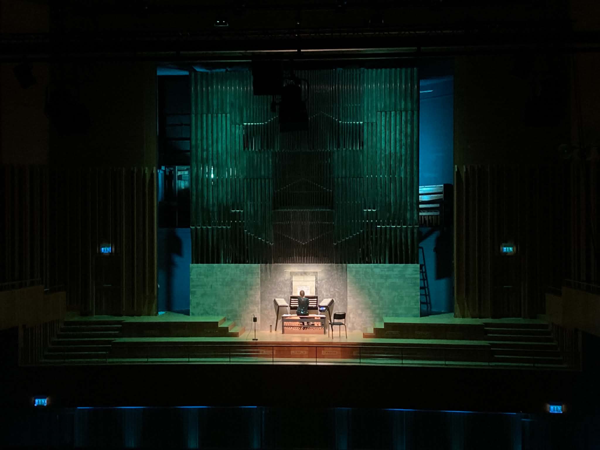 Den stora Orgel Acusticum i grön belysning. En av eleverna sitter och spelar på den och ser väldigt liten ut i förhållande till den enorma orgeln.