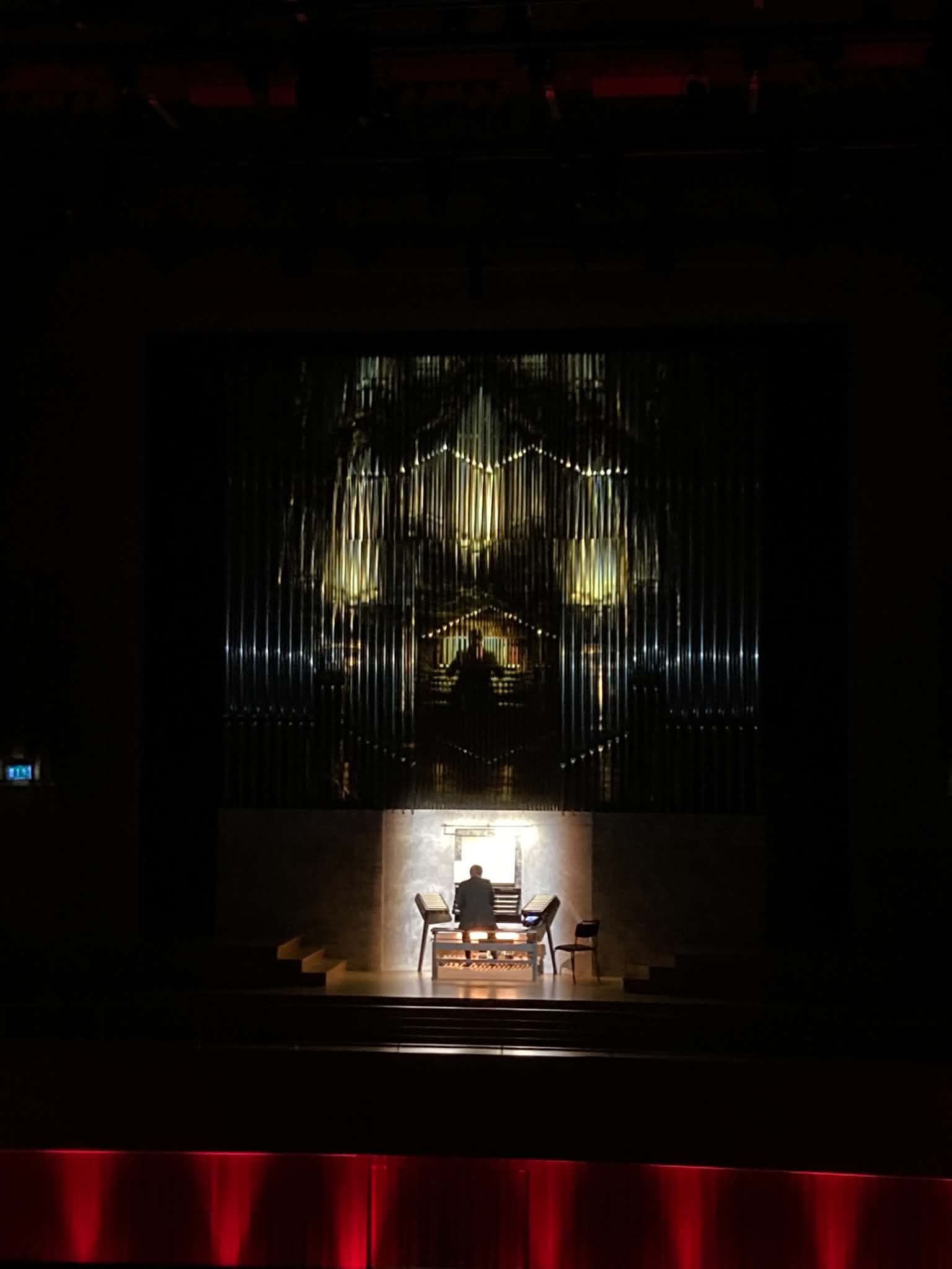 En upplyst orgel i gult scenljus med projektioner.