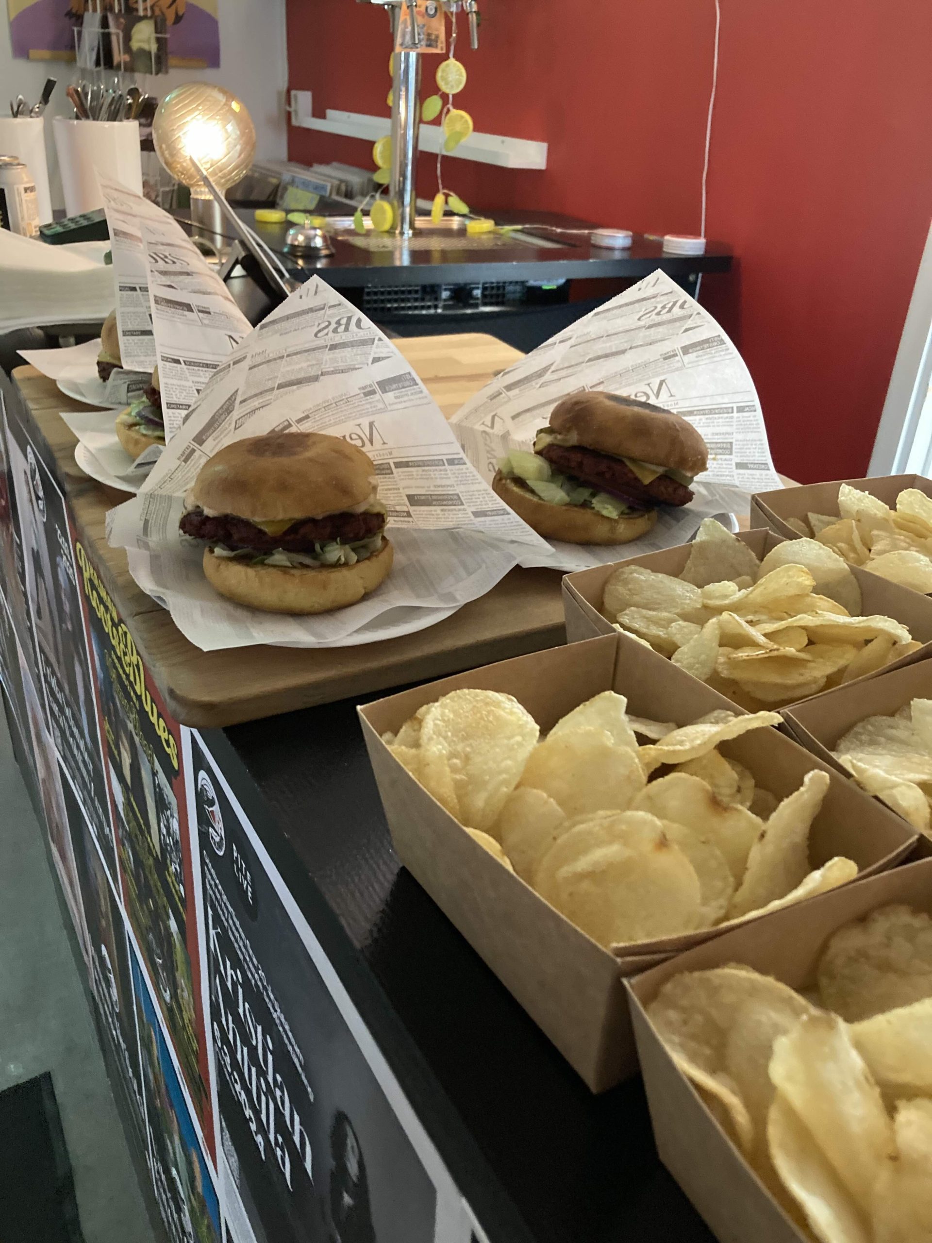 Chipsskålar i papp och burgare i pappersfickor på en bardisk.