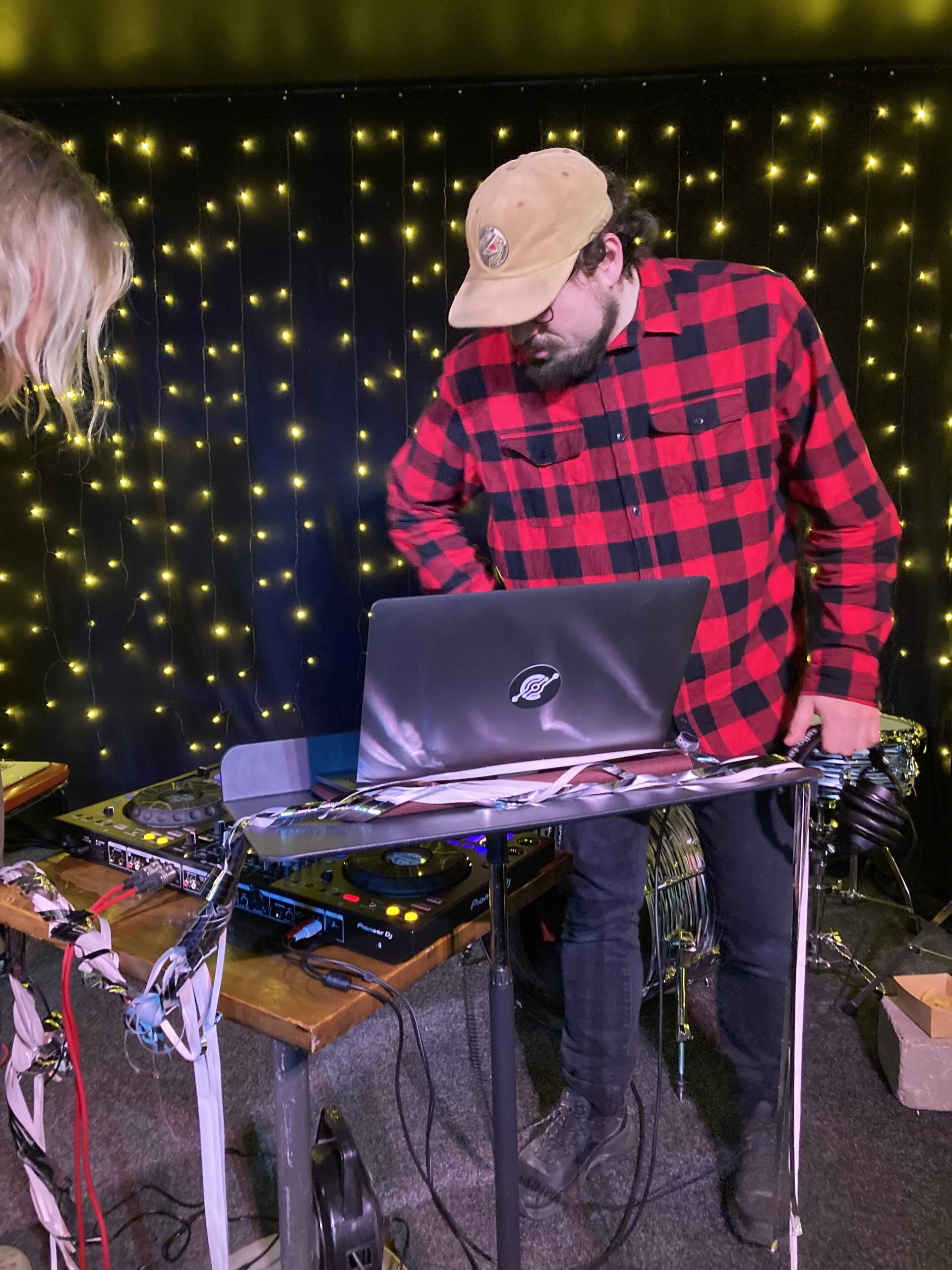En man står vid DJ-bordet med en laptop bredvid.