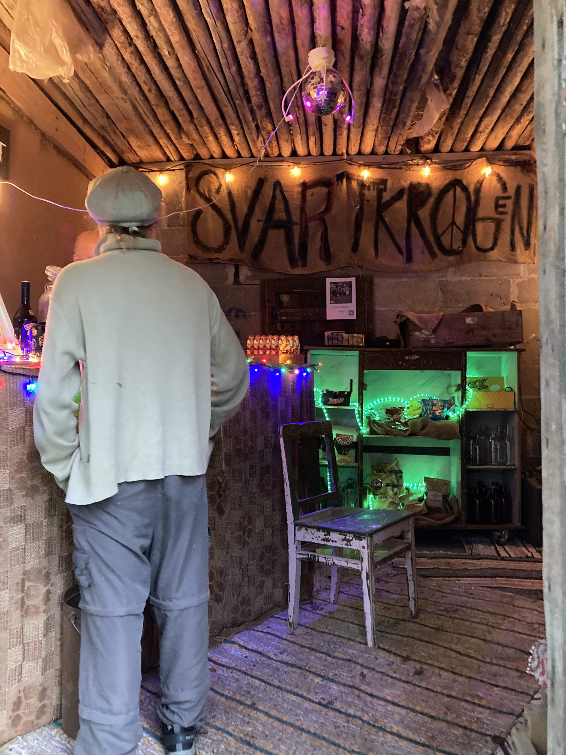 Ett rum i en lada med en bar och ljusslingor i olika färger. På en skylt står det "SvartKrogen".