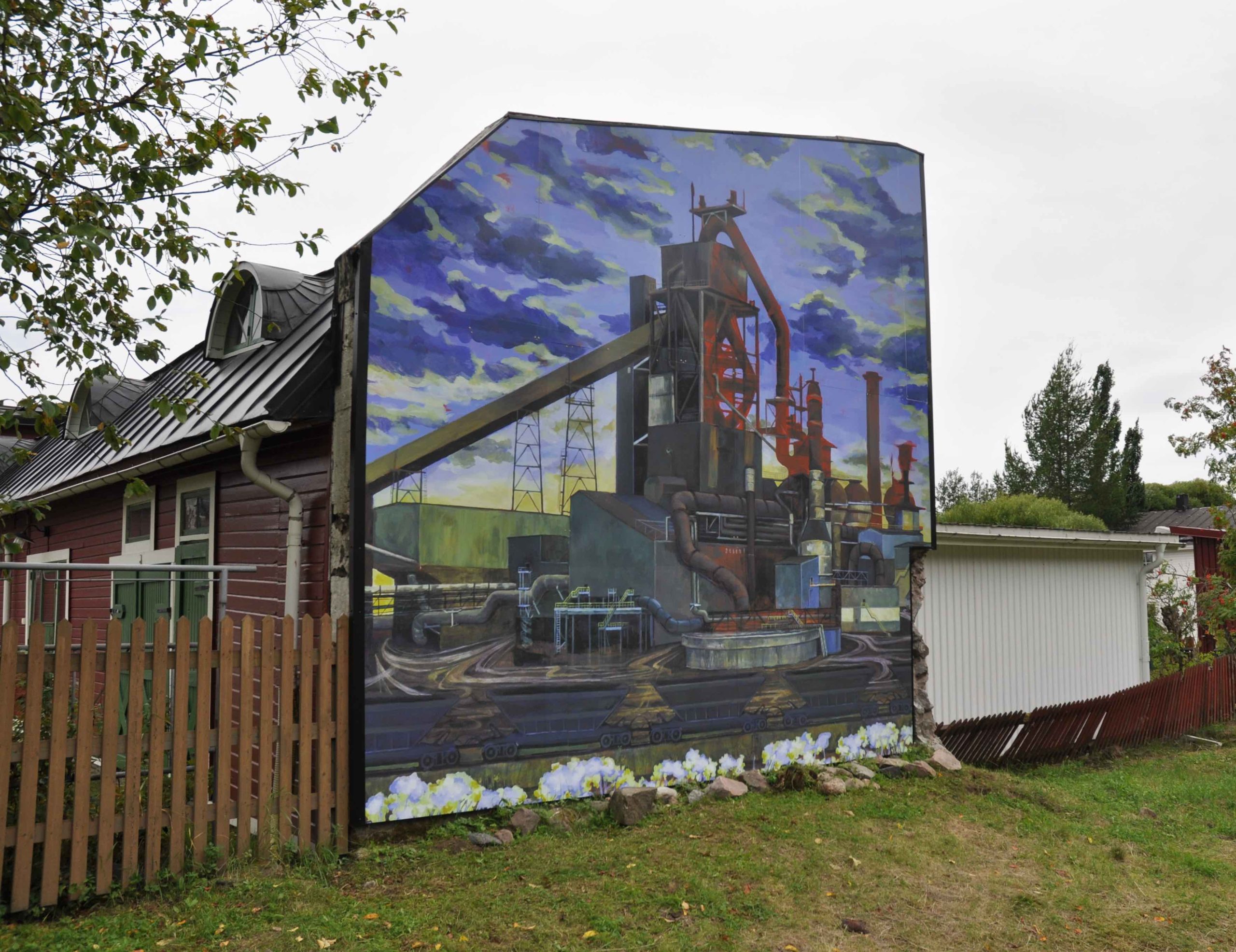 En vägg målad med graffiti. Målningen föreställer en del av SSABs fabrik.