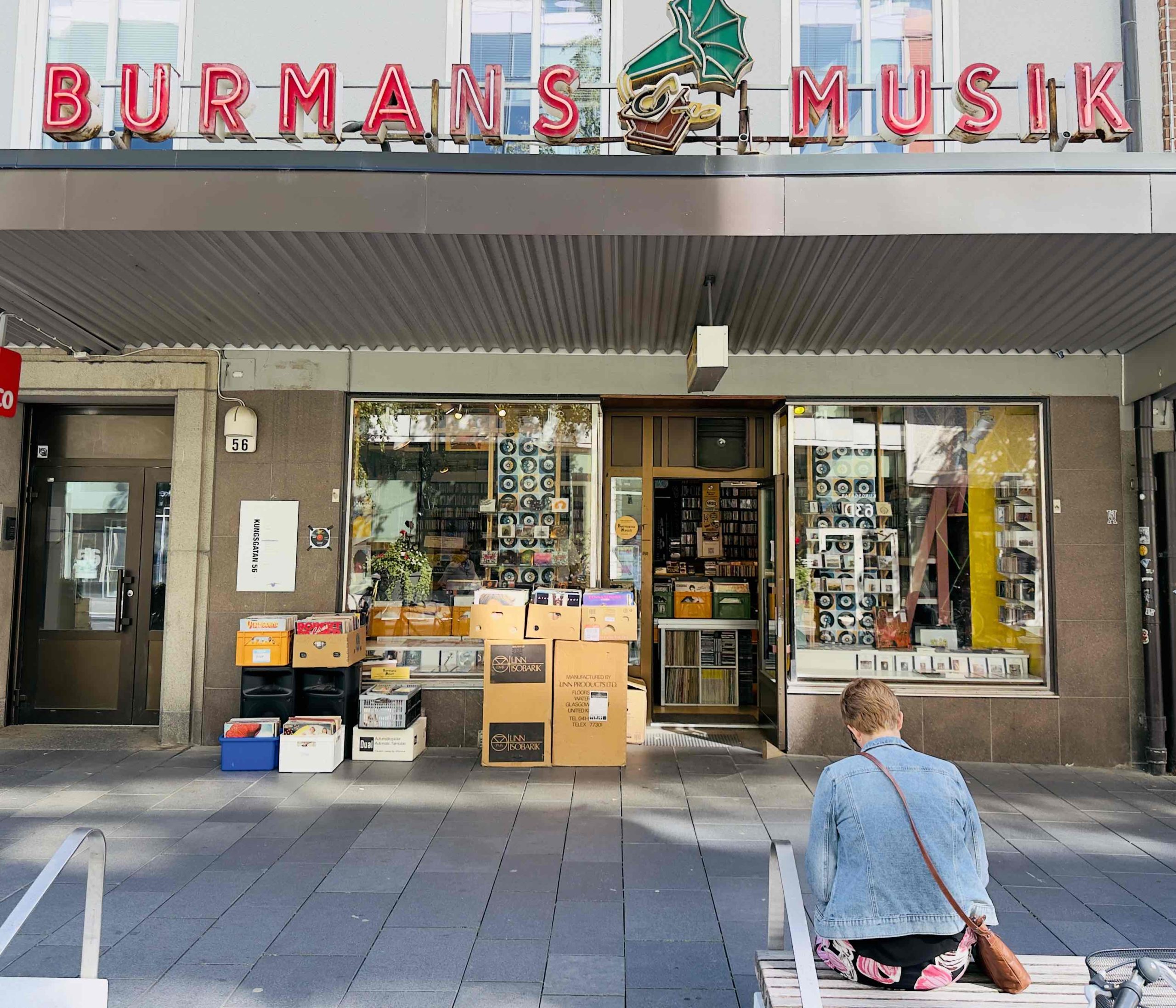 Foto på Burmans entré. En skylt med röda, stora bokstäver som bildar orden "Burmans Musik" med en grammofonspelare emellan orden. Skyltfönstren under skylten är fyllda med skivor.
