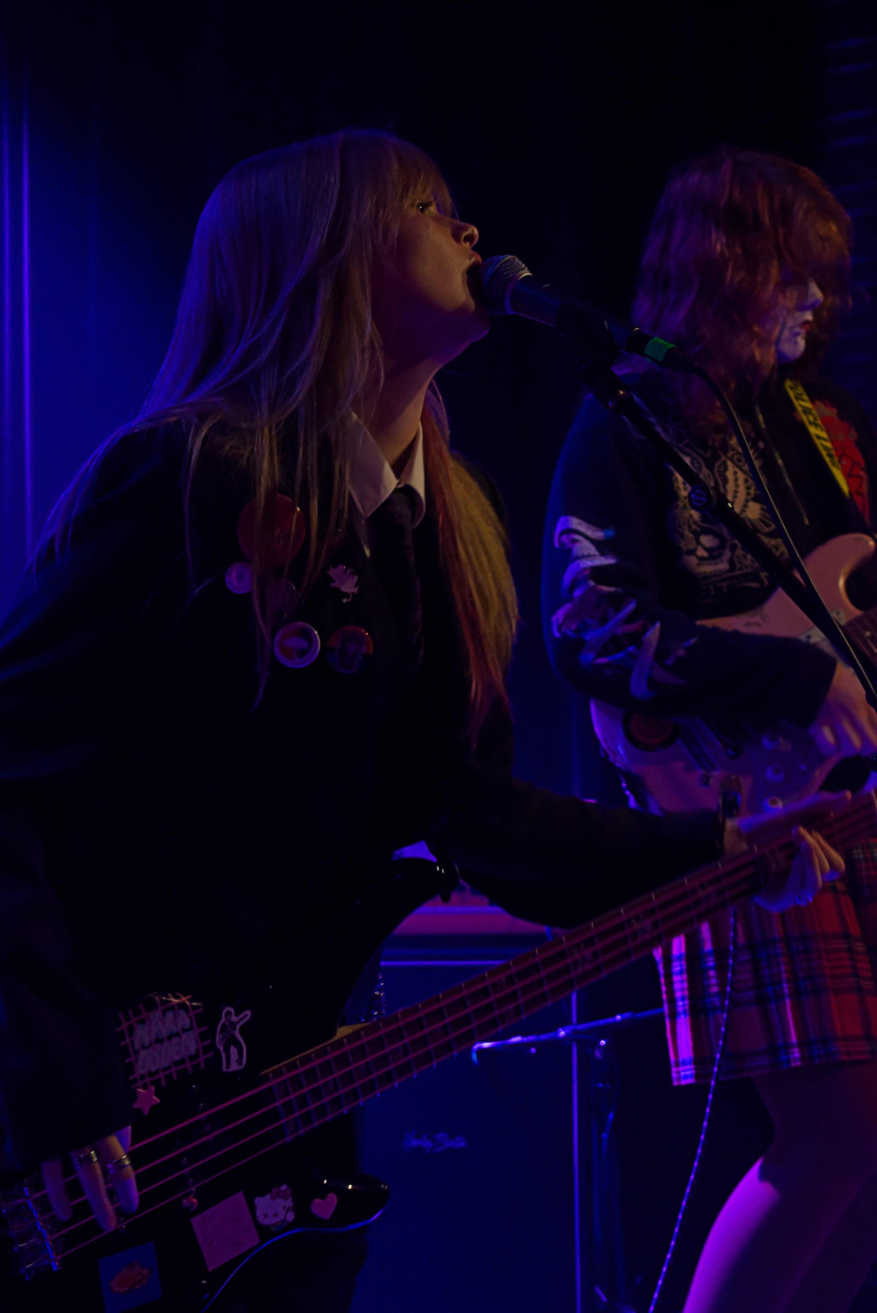 Lynchads basist och gitarrist. Basisten sträcker sig fram och sjunger i en mikrofon på ett stativ.