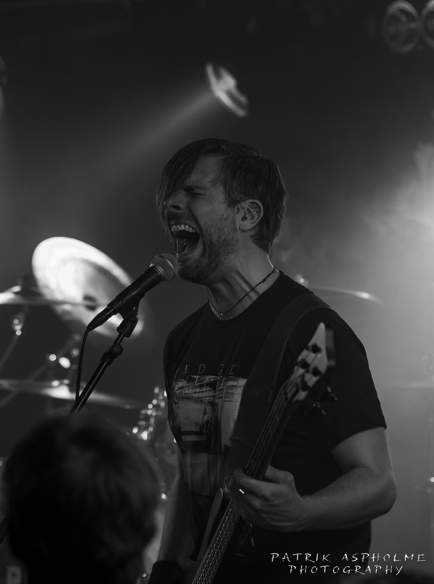 Left hand of darkness andra gitarrist skriker i mikrofonen med slutna ögon. Han har svart band-tshirt, kort hår och lång lugg.