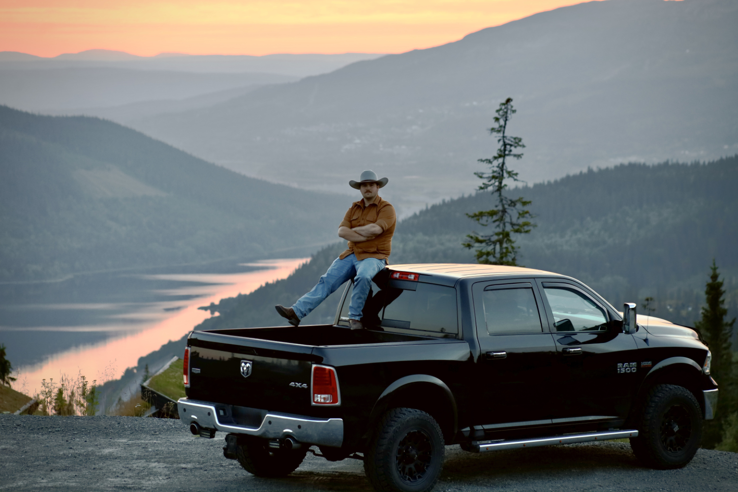 Laban sitter på flaket på sin jeep och i bakgrunden är det fjäll och vatten