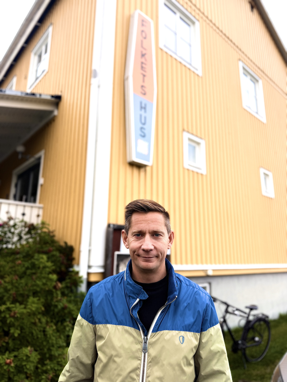 En man står framför ett gult Folkets Hus