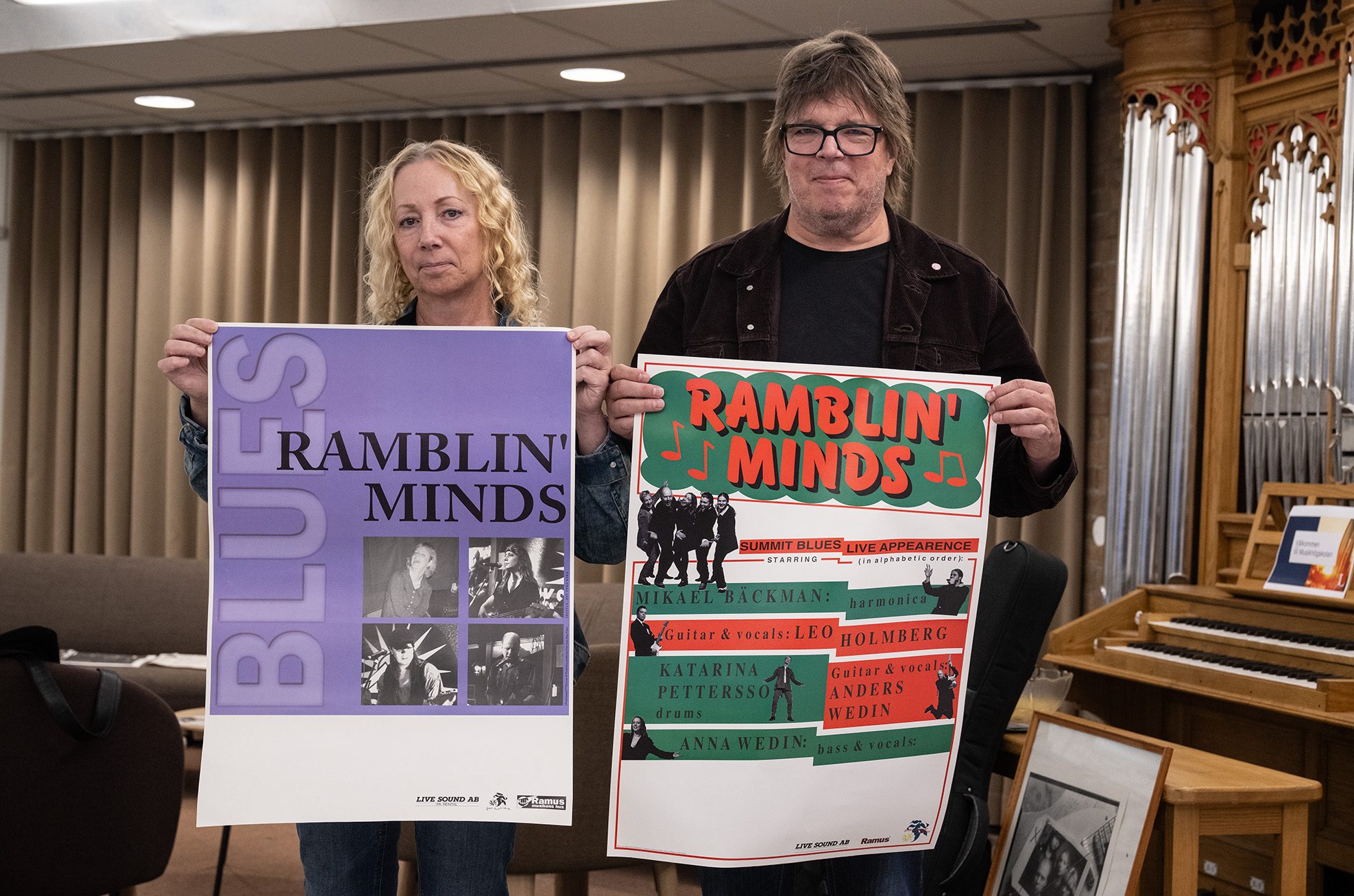 Basisten Anna och gitarristen Leo håller upp varsin affisch från två av bandets tidiga spelningar.